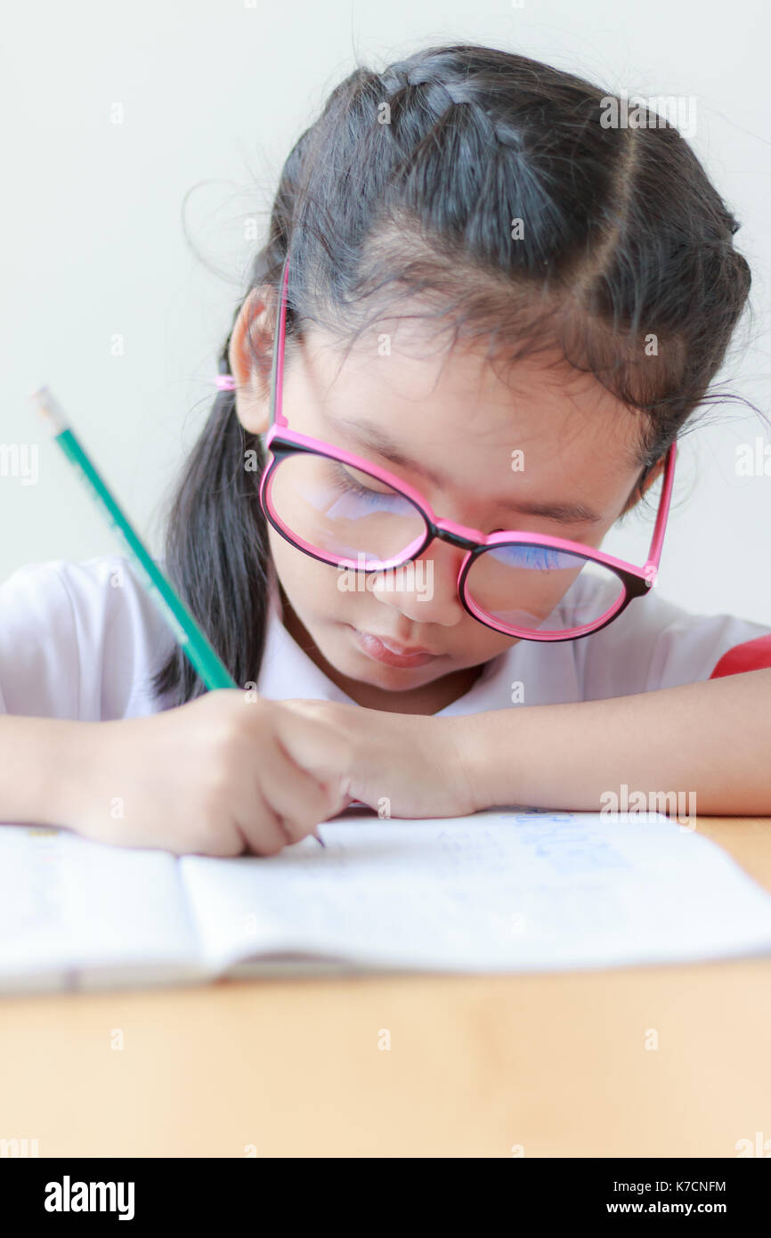Clolse bis Schuß Portrait von asiatischen Mädchen in Thai kindergarten Schüler einheitliche Hausaufgaben auf hölzernen Tisch Stockfoto