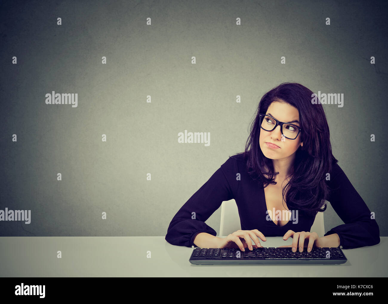 Ernsthaft beschäftigt, Frau sitzt am Schreibtisch mit der Eingabe auf der Tastatur eines Desktop-PCS Stockfoto