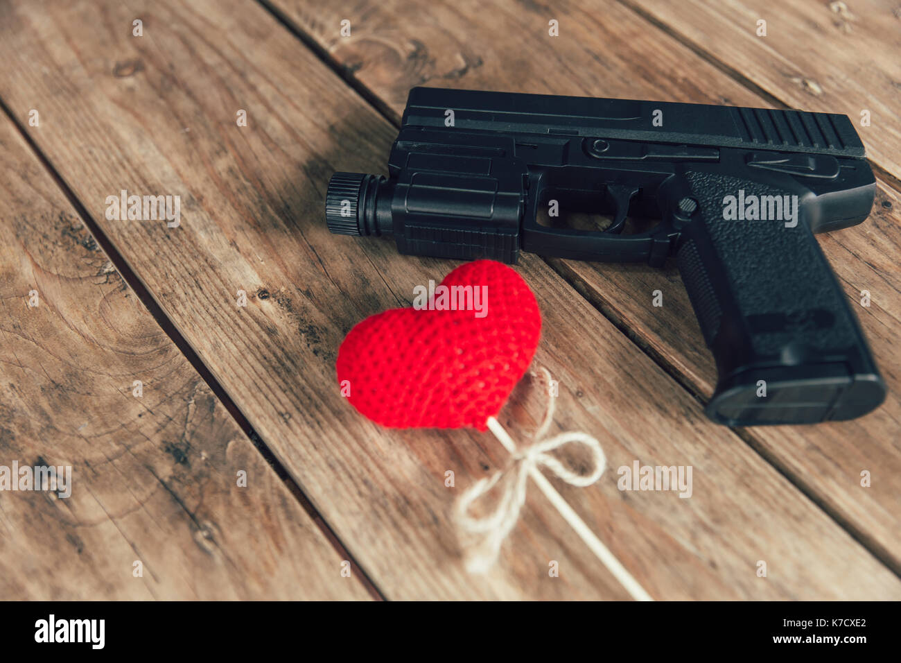 Pistole Pistole und Liebe rotes Herz auf Holz Hintergrund Stockfoto