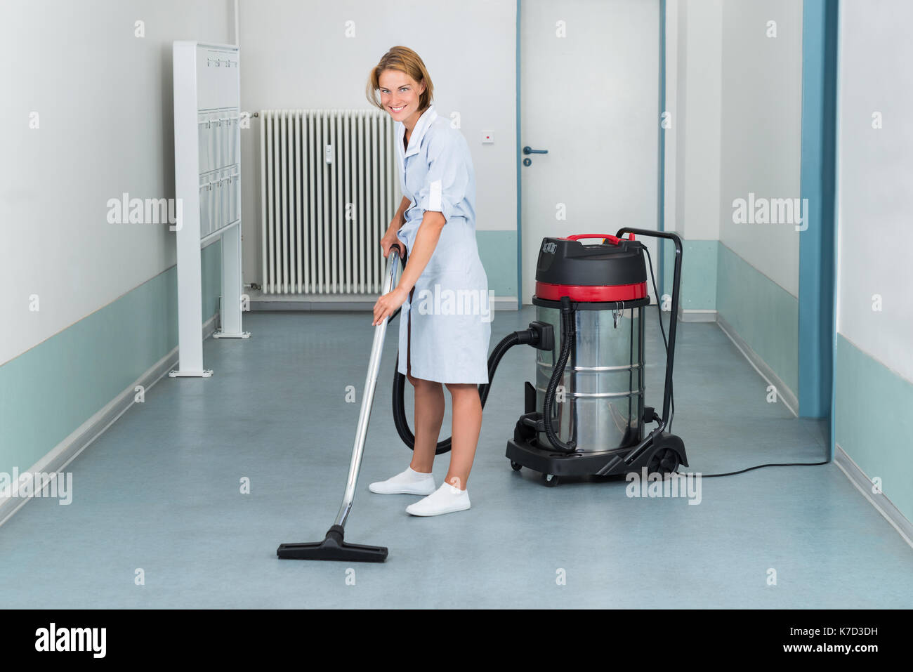 Junge weibliche Cleaner in Uniform absaugen, Stockfoto