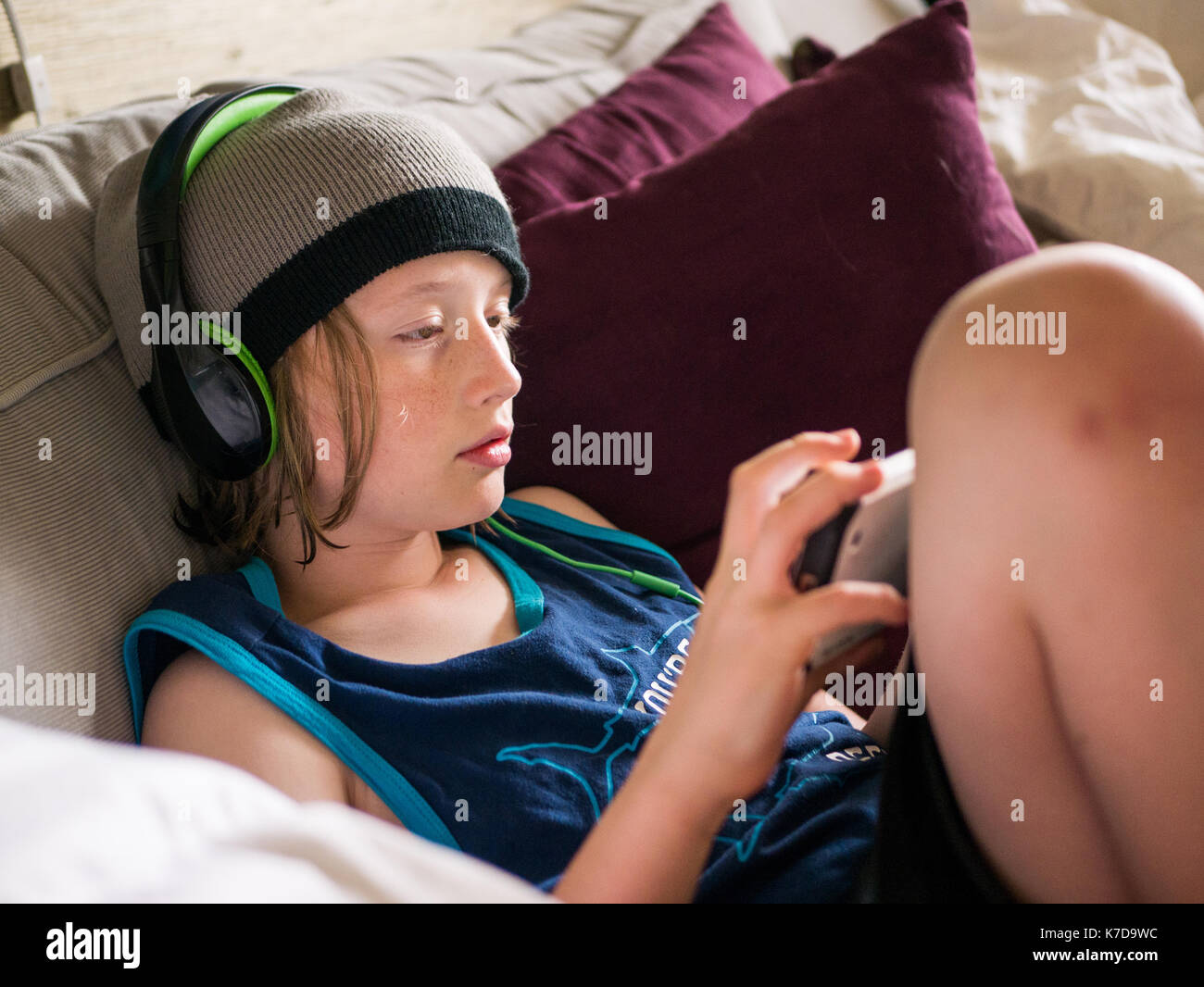 Hohe Betrachtungswinkel der Boy mit Smart Phone beim Hören von Musik zu Hause. Stockfoto