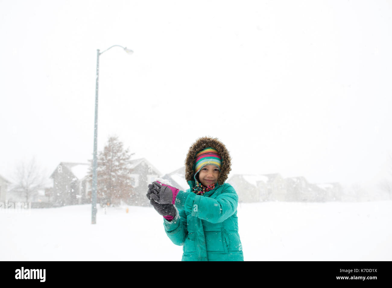 Portrait von glücklichen Mädchen in warme Kleidung spielen mit schneeball Stockfoto