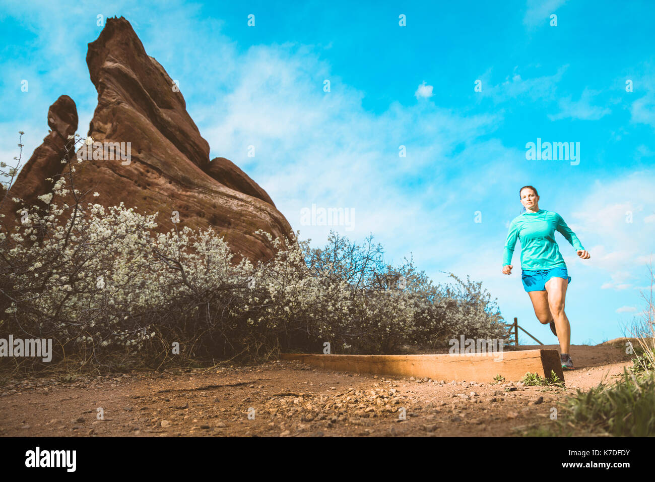 Bestimmt Sportlerin Jogging auf Schmutz weg vom Rock Formation gegen Sky Stockfoto