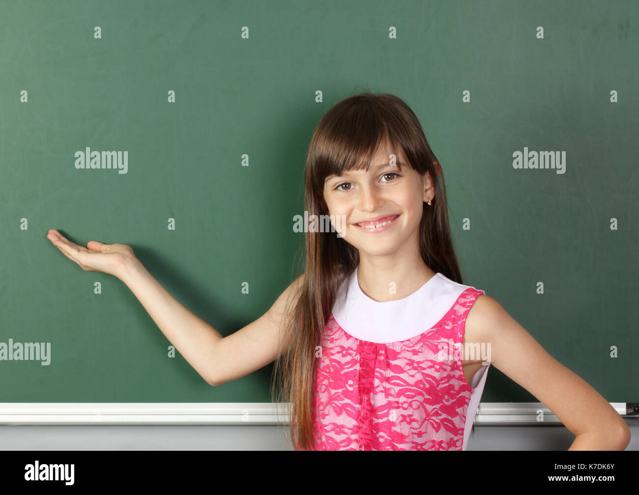 Lächelnd Kind hält seine Hand in der Nähe der leeren Schule Blackboard, Kopie Raum Stockfoto