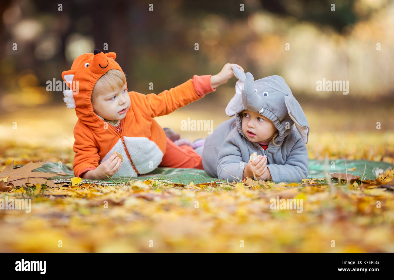 Kleine Kinder in Tierkostümen, junge gekleidet, wie Fox, Mädchen wie Elefanten, spielen im Herbst Wald Stockfoto