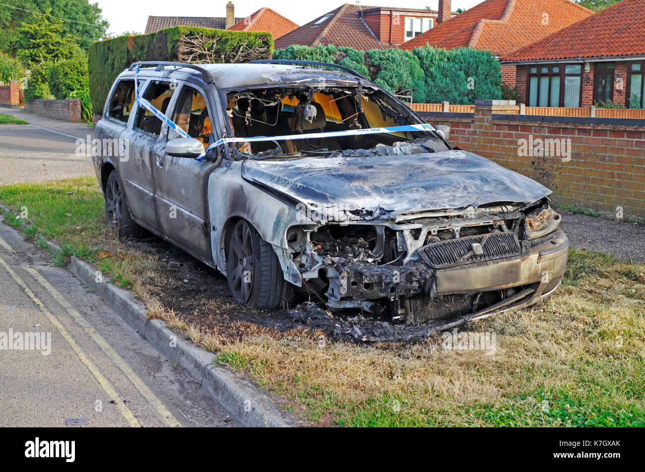Eine ausgebrannte Auto mit der Polizei Band am Straßenrand in Hellesdon, Norfolk, England, Vereinigtes Königreich. Stockfoto