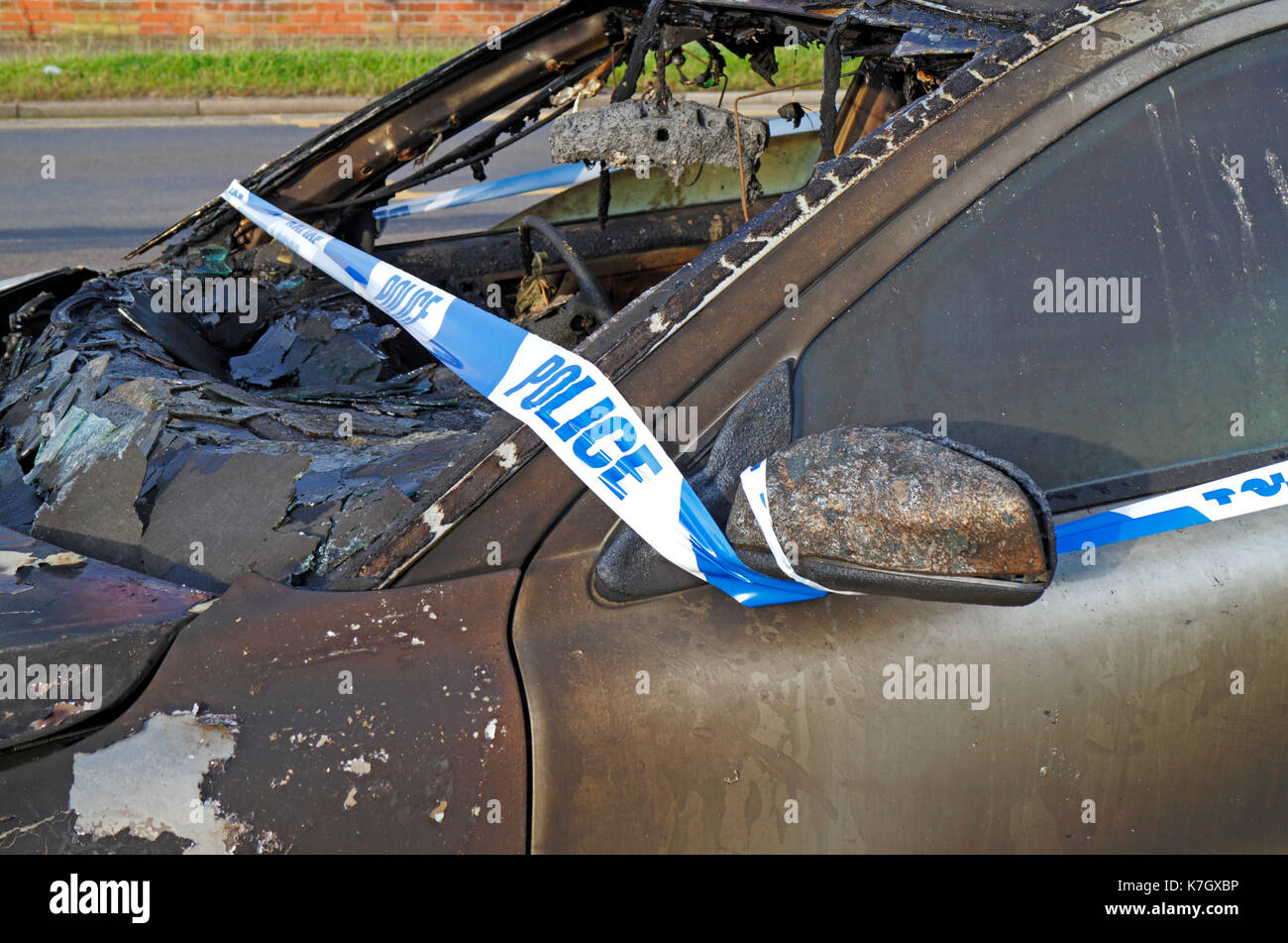 Eine ausgebrannte Auto mit der Polizei Band am Straßenrand in Hellesdon, Norfolk, England, Vereinigtes Königreich. Stockfoto