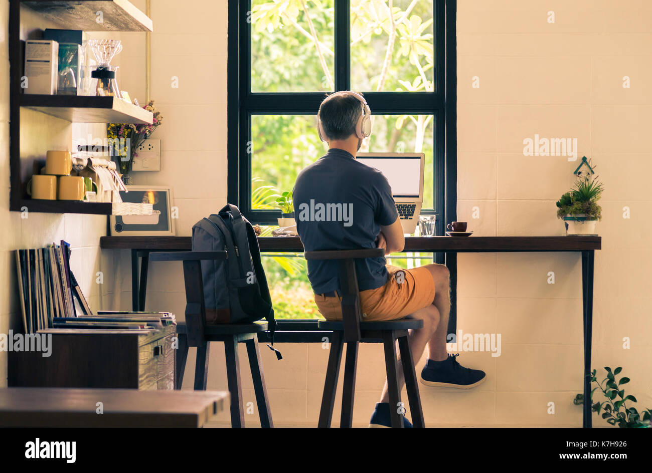 Mann in lässig-Tücher im Café sitzen mit seinem Laptop Computer und Kopfhörer, Vintage retor Farbton, gutes Foto für moderne und mobile Digita Stockfoto