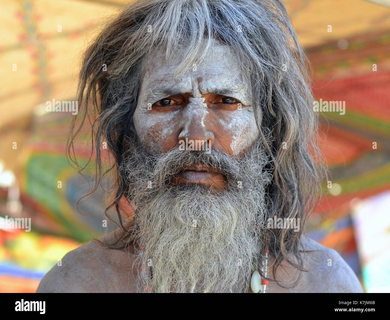 Indischer Hindu-Devotee (Sadhu) mit heiligem weißem Eschen (Vibhuti) im ganzen Gesicht und Bartposen für die Kamera. Stockfoto
