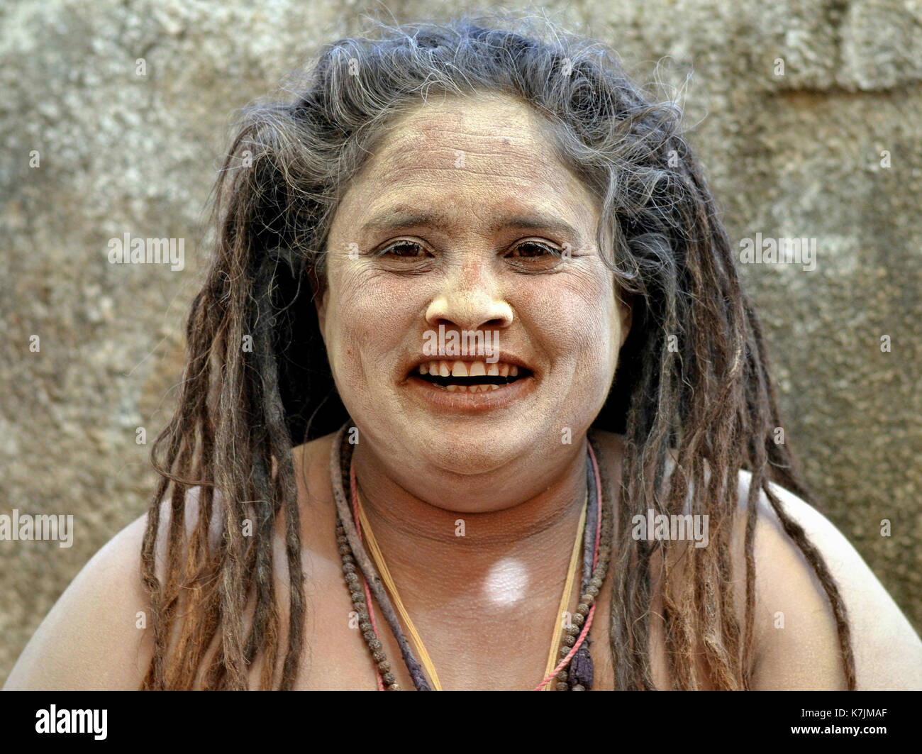 Die indische Hindu-Frau Sadhu (Sadhvi) mit langen Dreadlocks und einem feierlichen weißen Makeup aus heiligem Eschen (Vibhuti) lächelt für die Kamera. Stockfoto