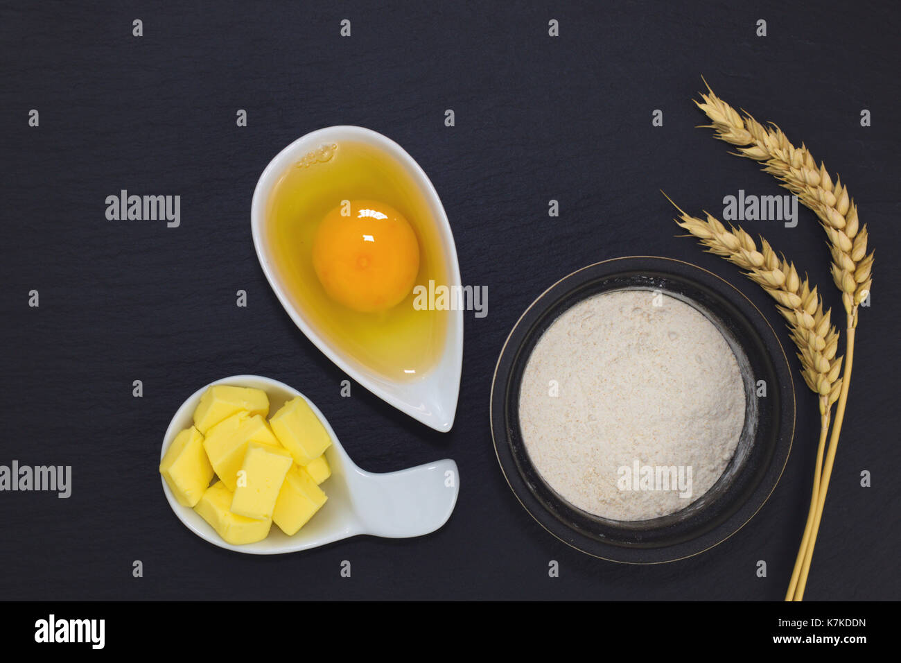 Essen Konzept der Bäckerei Zutaten Mehl, Ei und Butter auf schwarzem Schiefer Platte Stockfoto