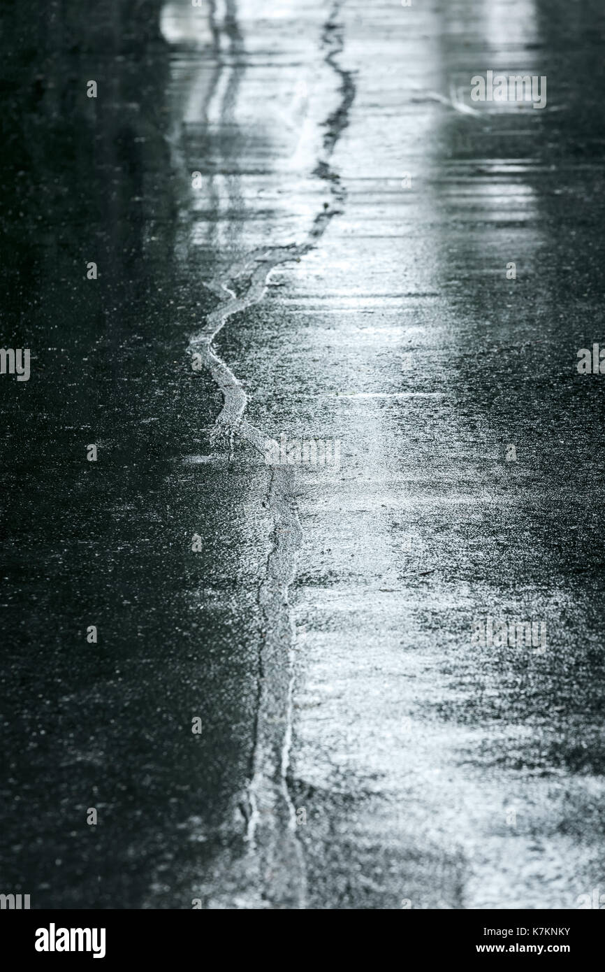 Nasser asphalt Bürgersteig in regnerischen Tag. Wasser Pfützen auf der Straße Fahrbahn. Stockfoto