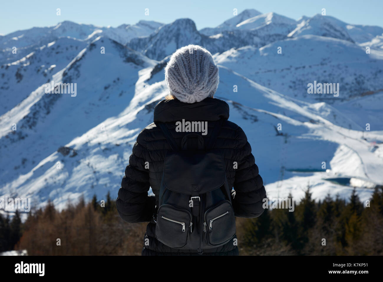 Frau mit Hut und Rucksack wolle mit Blick auf die Berge mit Schnee an einem sonnigen Wintertag Stockfoto