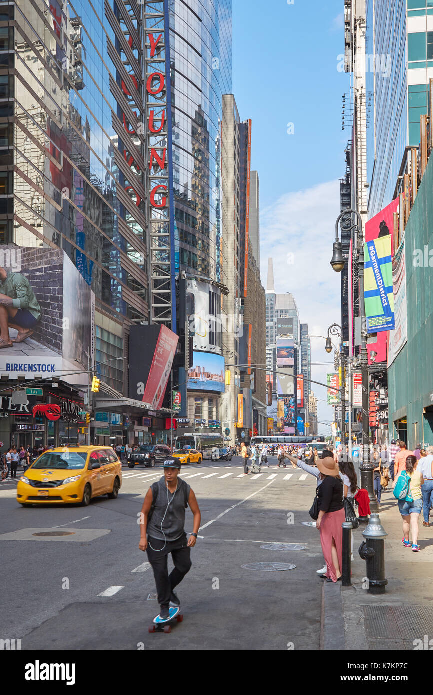 Die Fifth Avenue mit Skate Board Mensch und Leute, die ein gelbes Taxi, Wolkenkratzer und blauer Himmel in New York Stockfoto