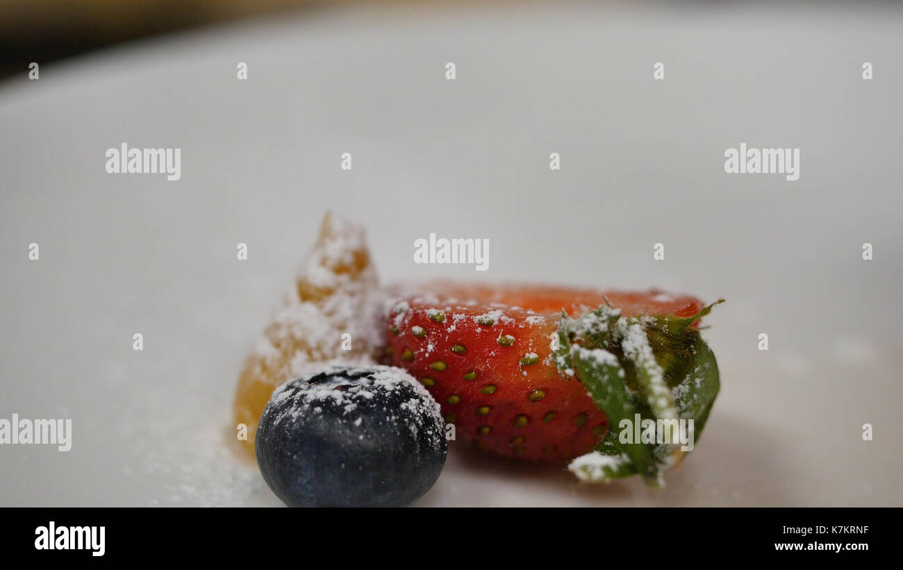 Erdbeeren und Blaubeeren mit Puderzucker Streuseln. Das Streuen von Puder auf die Erdbeeren, Blaubeeren Stockfoto
