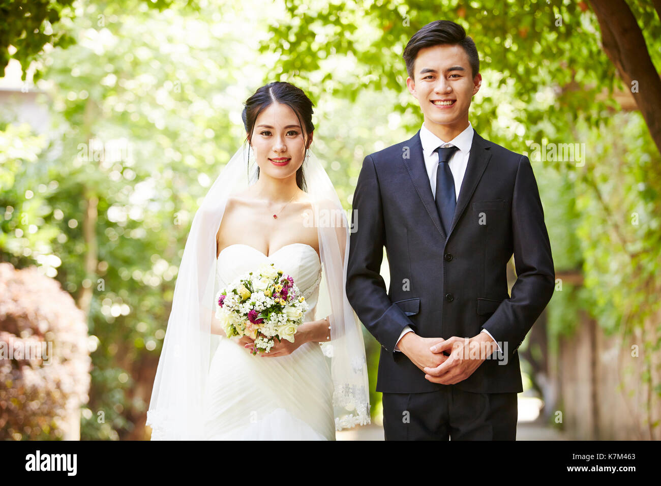 Outdoor Portrait von asiatische Braut und Bräutigam an der Kamera schaut lächelnd. Stockfoto