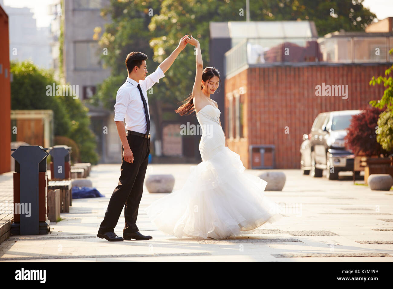 Junge asiatische Braut und Bräutigam in Wedding Dress tanzen auf dem Parkplatz. Stockfoto