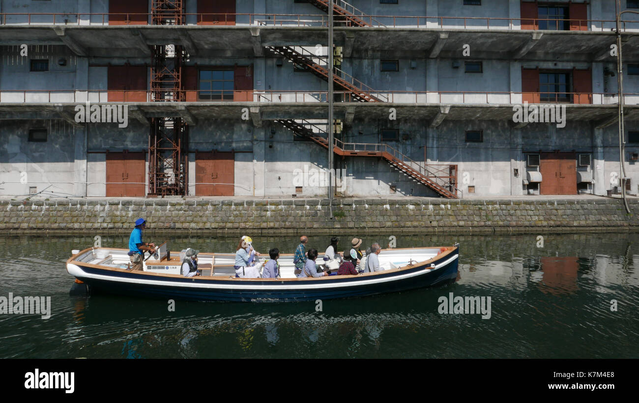 Tour Boot vorbei vor der historischen Hokkai können Fabrikgebäude in Otaru Japan Schatten von Boot und Gebäude in Kanal keine an der Kamera schaut. Stockfoto