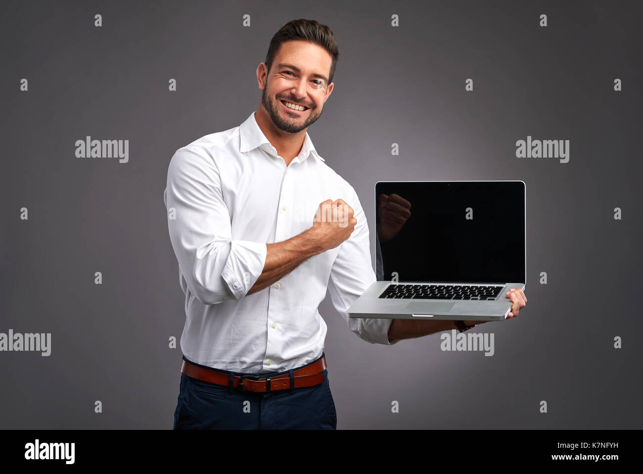 Ein hübscher junger Mann hält und zeigt den Bildschirm eines Laptops und feiern Stockfoto
