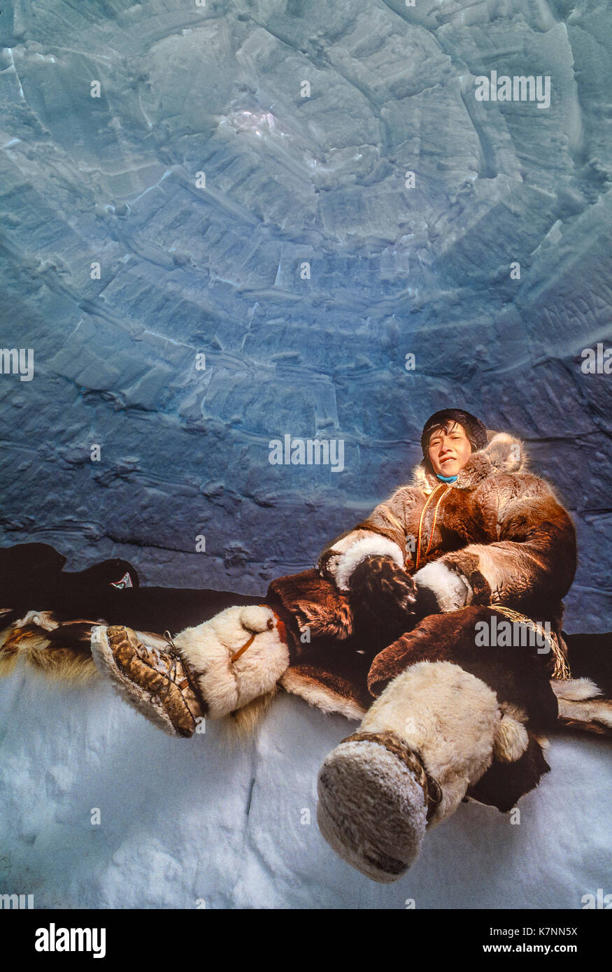 Besucher in traditionellen Caribou haut Kleidung sitzt auf Caribou Skins auf eine schlafende Sims im Iglu, wo sie Campingplatz für eine Woche. Außerhalb Baker Lake, Nunavut, Kanada. Stockfoto