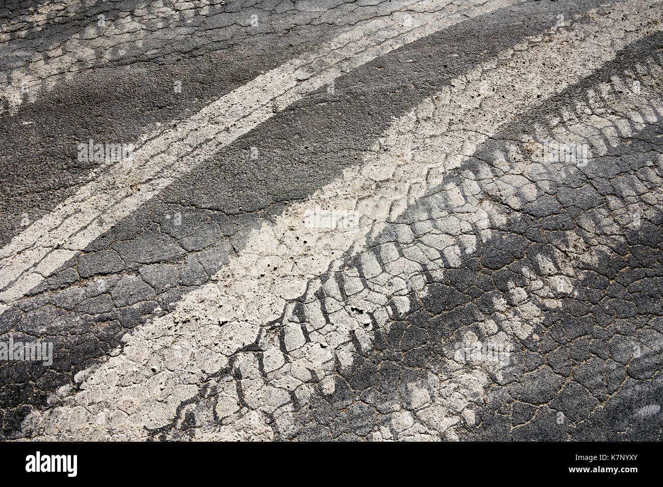 Muddy Reifenspuren auf Risse Fahrbahn vom Bauernhof Fahrzeuge - Frankreich. Stockfoto