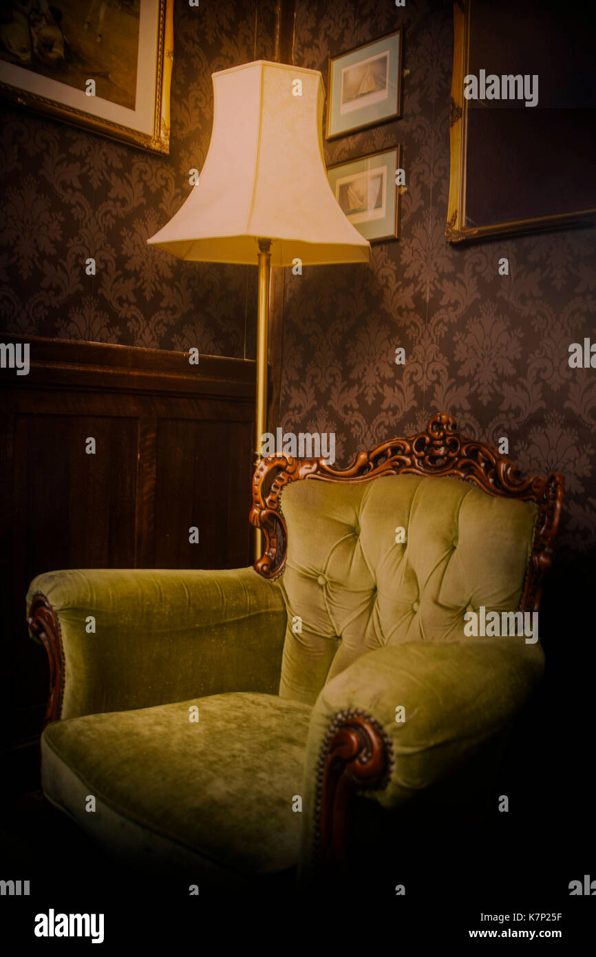 Bild eines alten bequemen Sessel im Wohnbereich mit einer Prüflampe und stimmungsvoller Beleuchtung Stockfoto