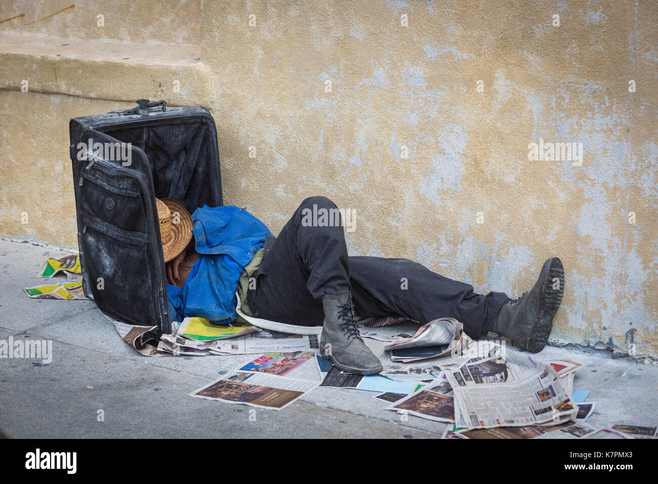 Liegenden Mann mit Kopf im Koffer, vermutlich obdachlos, in Downtown, Los Angeles, im Fashion District, in der Nähe von Skid Row. Stockfoto