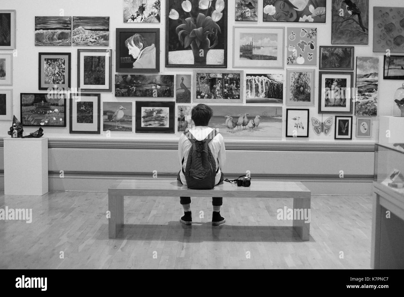 Junger Mann mit einer Kamera an eine Kunstgalerie im Sitzen. Stockfoto
