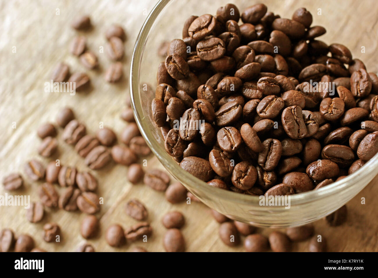 Geröstete Kaffeebohnen in Glas auf hölzernen Tisch Stockfoto