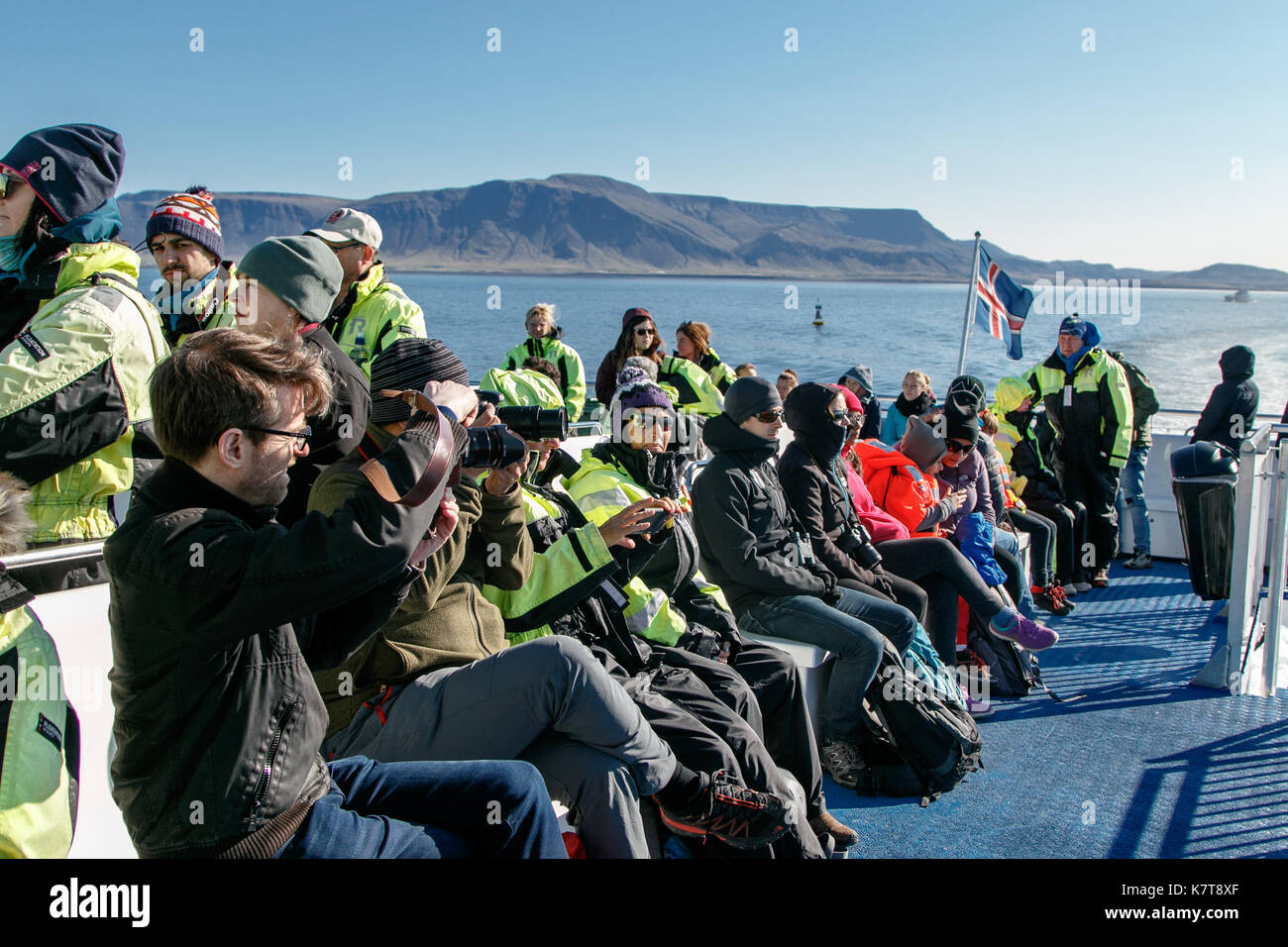 Menschen tragen warme Overalls reiten Boot während eine Whale Watching Tour an einem sonnigen Nachmittag. Stockfoto