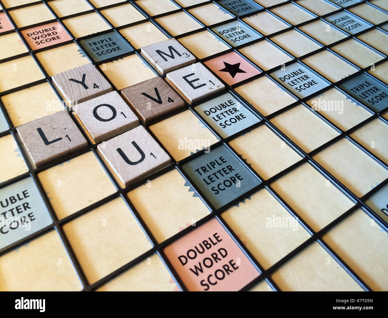 Die Worte "Sie lieben mich" heraus auf einem Scrabble-Spiel board geschrieben. Stockfoto