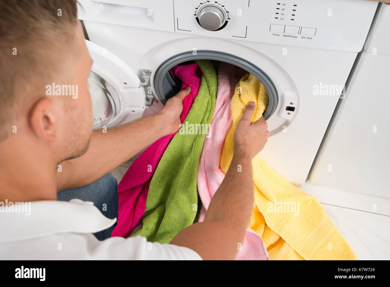 Close-up des jungen Mannes Laden Bunte Handtücher in der Waschmaschine Stockfoto