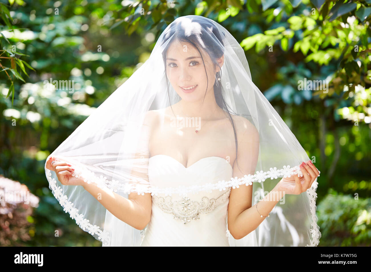Outdoor Portrait von schönen und fröhlichen jungen asiatischen Braut tragen Bridal Veil. Stockfoto