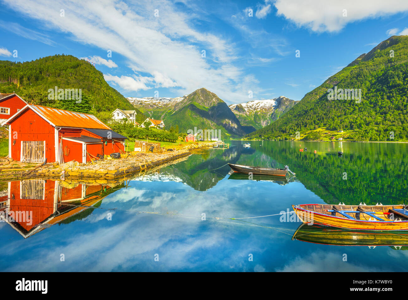 Die schneebedeckten Berge und roten Bootshaus, Reflexion in das blaue Wasser des Sognefjord an Balestrand, Norwegen, Skandinavien Stockfoto