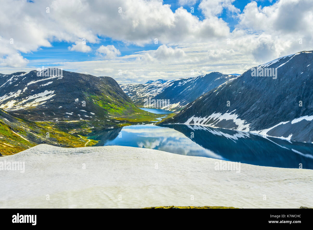 Mountain Lake Djupvatnet mit Reflexion und Schneefeld im Vordergrund, unter dem Berg Dalsnibba in der Nähe Geiranger, Norwegen Stockfoto
