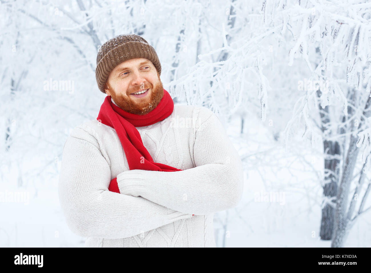Junge rothaarige Mann mit Bart in Mütze und Schal im Winter Wald. Portrait von glücklichen Menschen mit stilvollen roten Bart und Schnurrbart in Winter Park Hintergrund. P Stockfoto