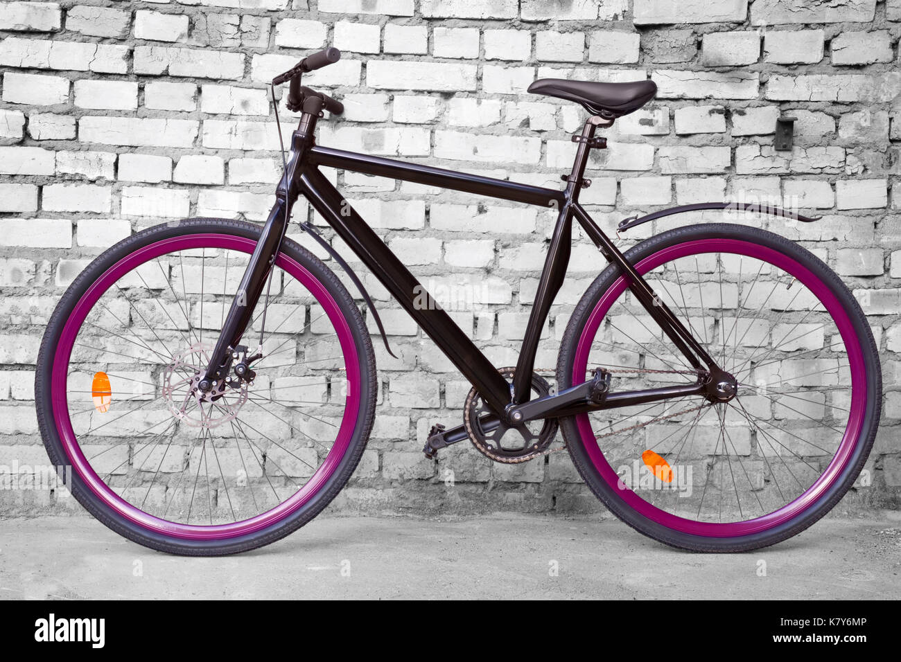 Schwarz feste Urban Bike mit violetten whels gegen schwarze und weiße Wand Stockfoto