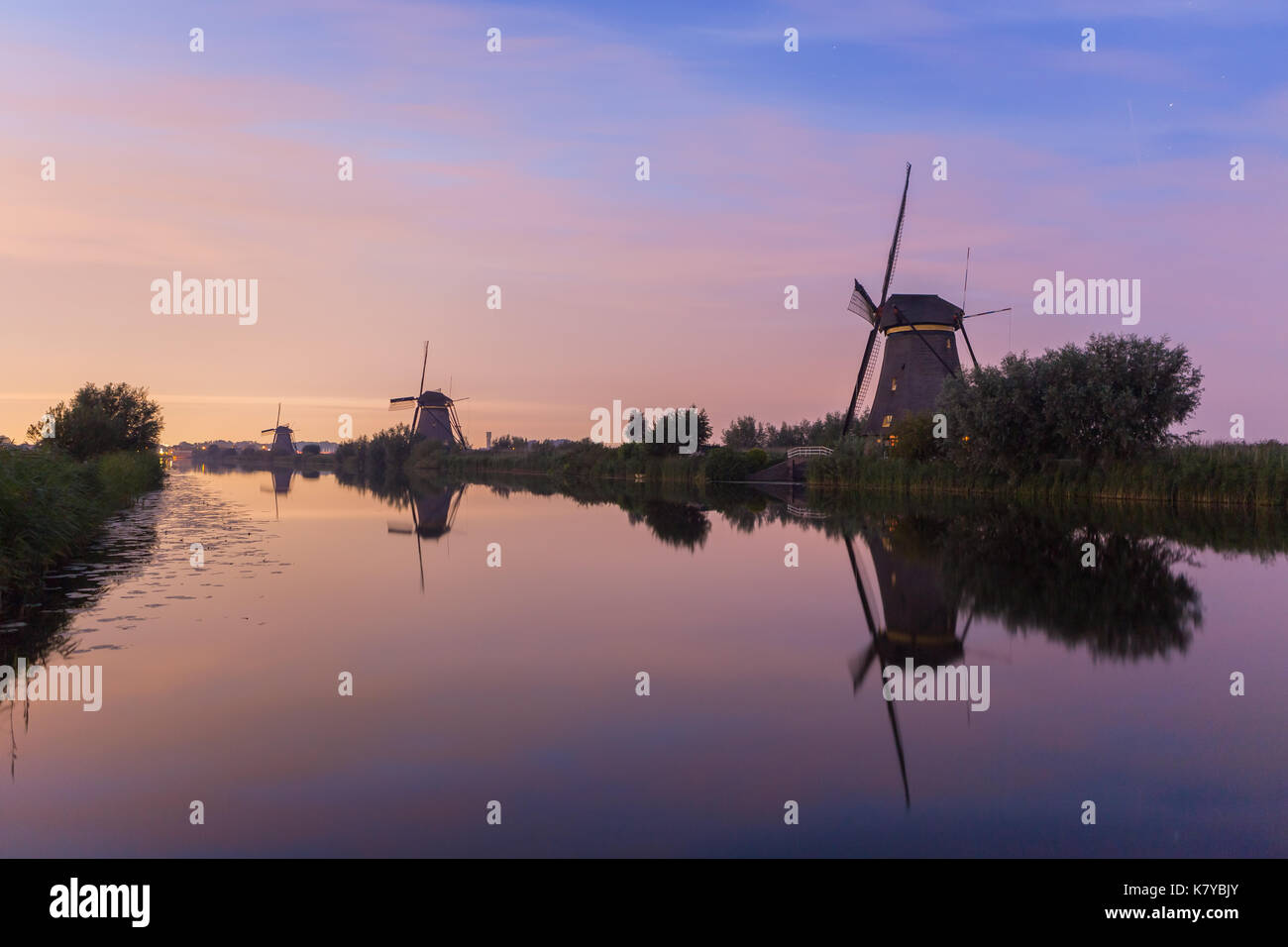 Die Windmühlen von Kinderdijk, ein Weltkulturerbe der UNESCO, an der Wasserseite bei Sonnenuntergang gesäumt. Neben Windmühlen, die Seite zeigt verschiedene andere 57,96 Stockfoto