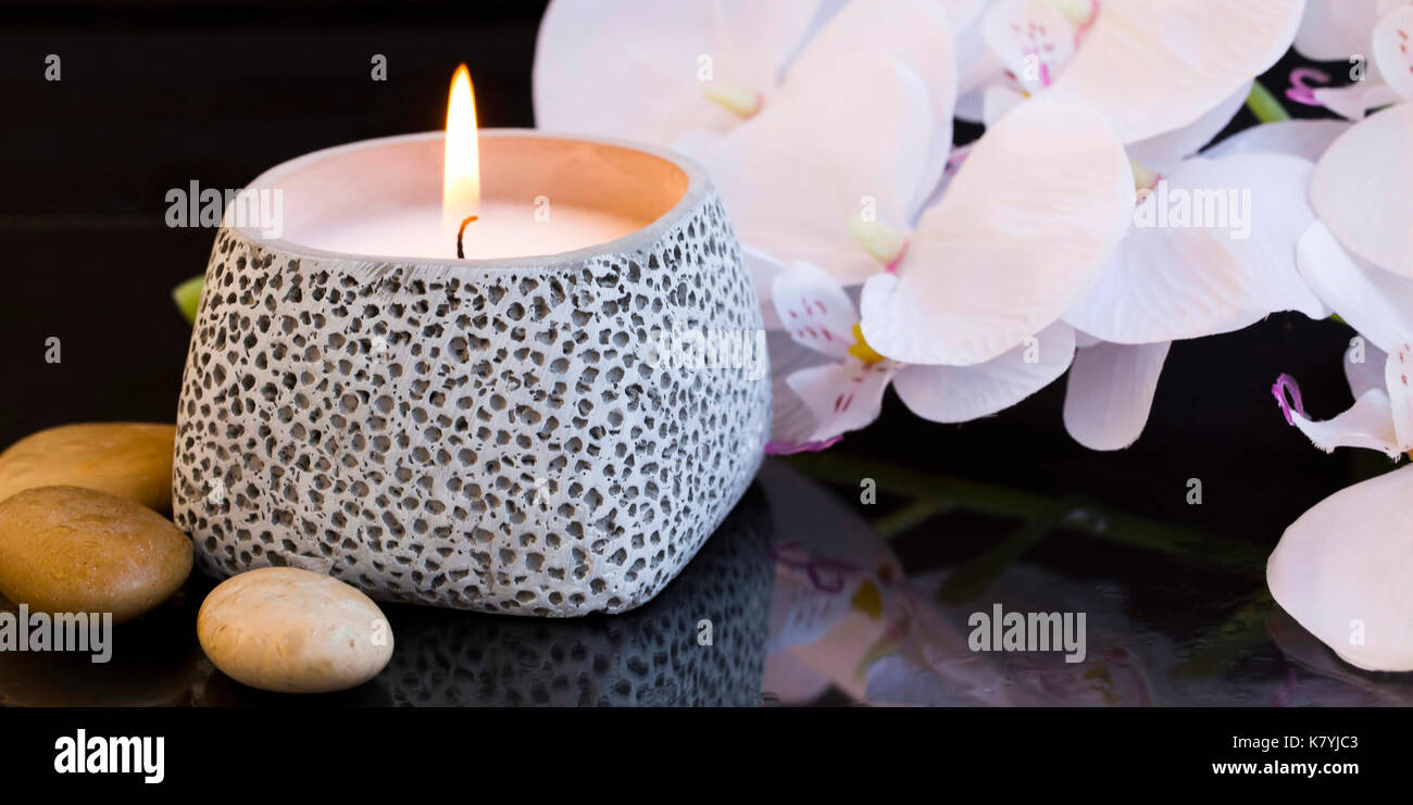 Spa Kerze mit Orchideen und Massage Steine Stockfoto