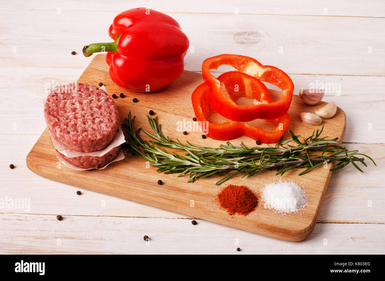 Rohes Hackfleisch burger Schnitzel mit roten Zwiebeln, Knoblauch, Oliven und Paprika Öl auf einem weißen Holz- Hintergrund Stockfoto