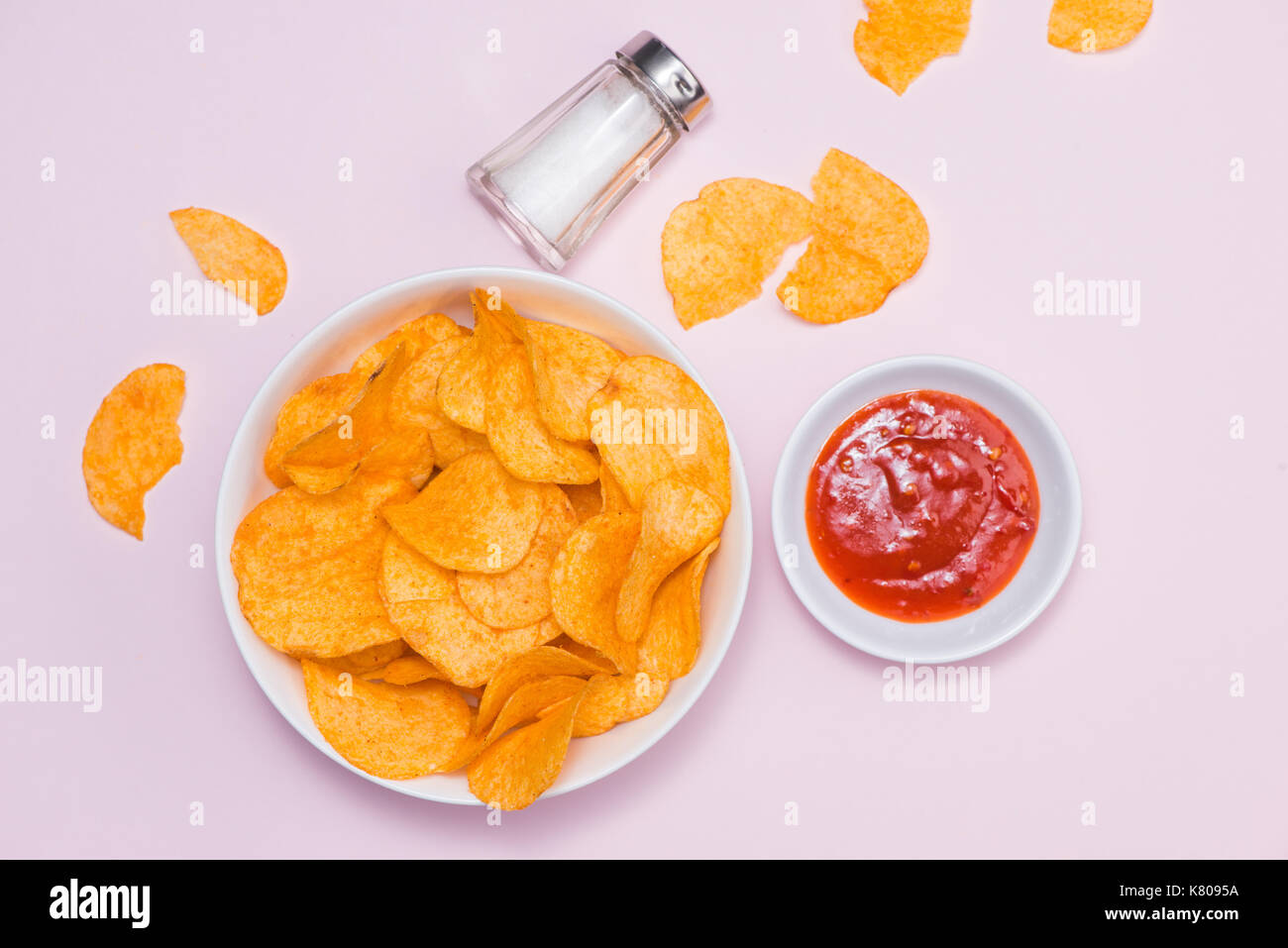 Konzept für ungesunde Lebensmittel. Käse und Zwiebel-Kartoffel-Chips mit hot Chilisauce auf rosa Hintergrund. Stockfoto