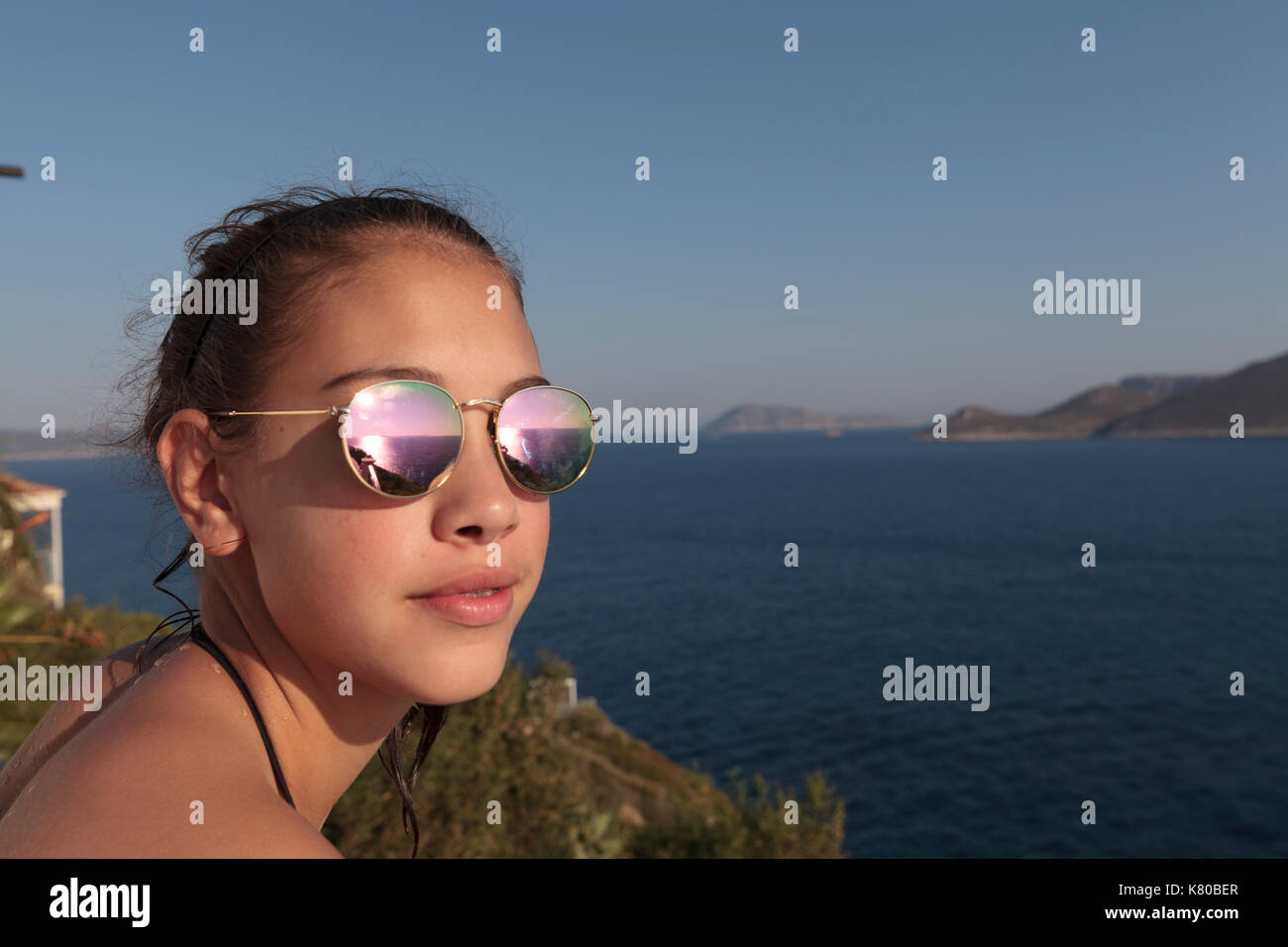 Junges Mädchen mit Sonnenbrille mit Blick über das Meer zu Meis Stockfoto