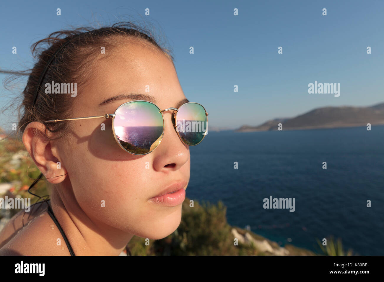 Junges Mädchen mit Sonnenbrille mit Blick über das Meer zu Meis Stockfoto