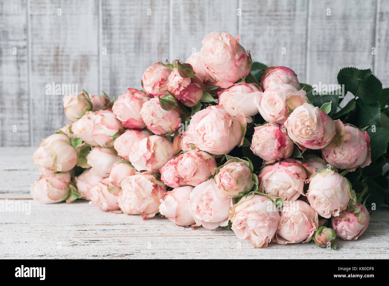Blumenstrauß aus schöne rosa Strauchrosen auf alten weißen Tisch. Wedding Bouquet, Blumen, Blumenmuster frame-Konzept. Horizontale Zusammensetzung Stockfoto