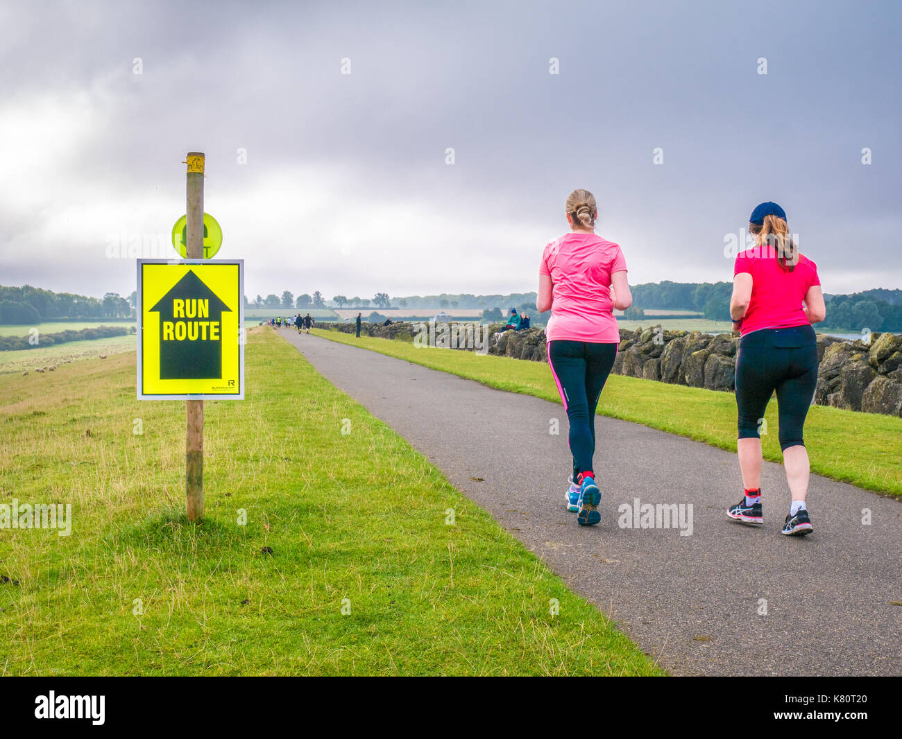 Bringen Sie den hinteren, der letzte Läufer auf dem Weg über den Damm zu Beginn der Rutland Marathon und Halbmarathon Rennen in Rutland Water Reservoir, England, am Sonntag, den 17. September 2017 Stockfoto