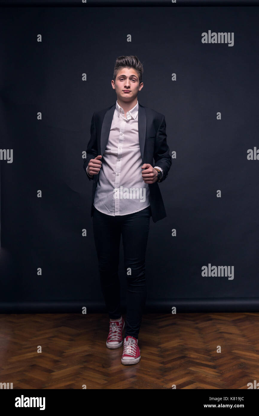 Ein junger Teenager, schwarzer Hintergrund, Studio, Anzug posiert, formelle Kleidung Stockfoto