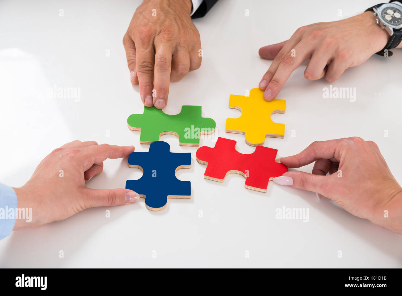 Close-up von Menschen Montage bunte Puzzleteile am Schreibtisch Stockfoto