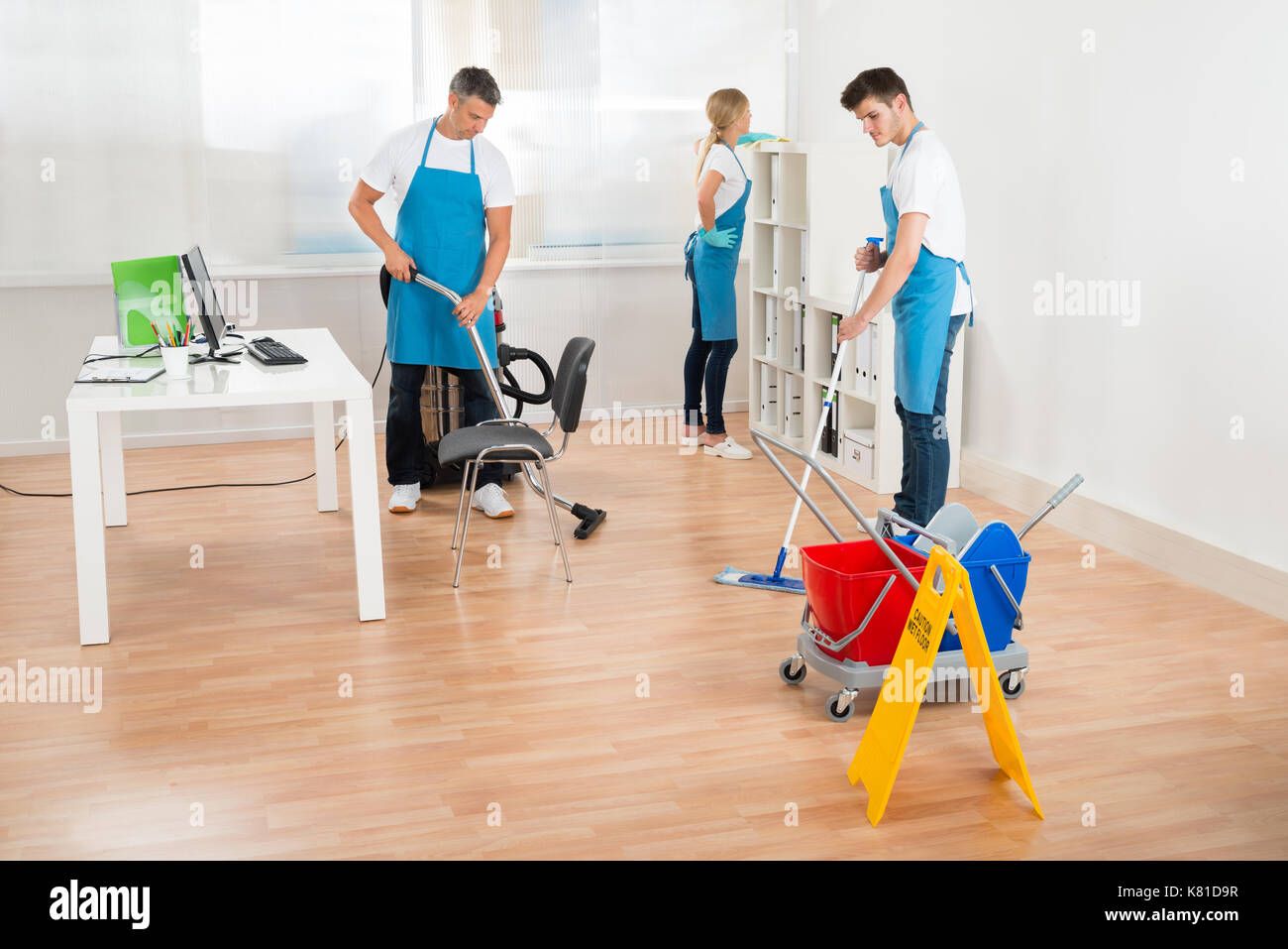 Gruppe von drei Hausmeister in der blauen Schürze Reinigung Büro Stockfoto