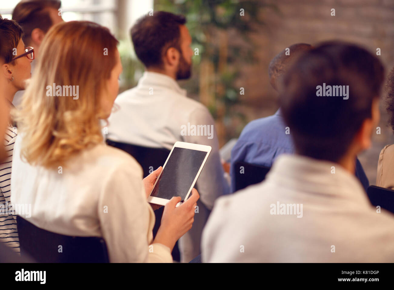 Rückansicht der Frau mit Tablette auf Vortrag in der Kongresshalle Stockfoto