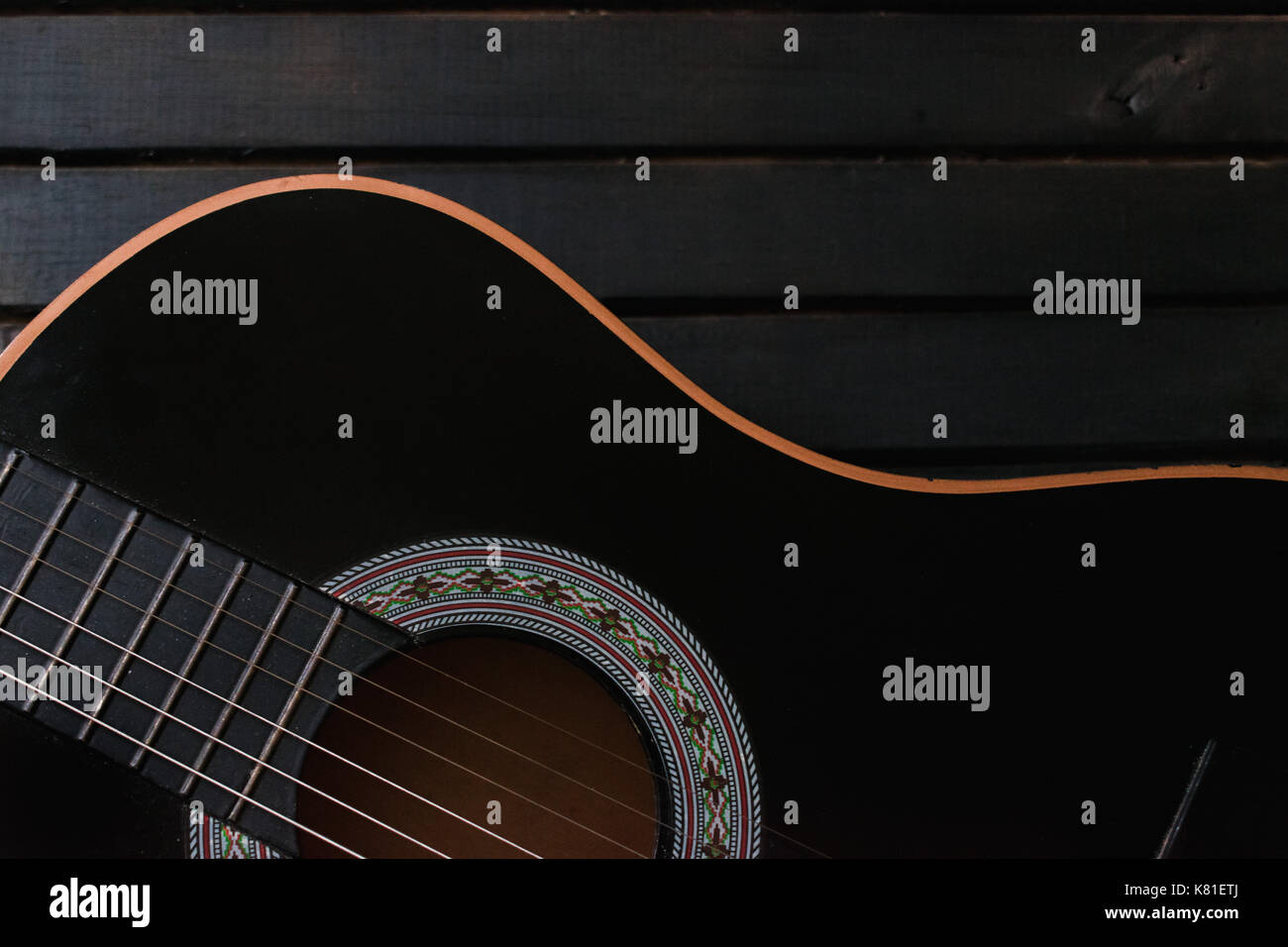 Schwarz akustische Gitarre, Nahaufnahme, auf einem schwarzen Holz Tisch Hintergrund, mit vielen Textur, mit der Gitarre Form Stockfoto